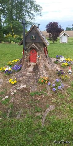 a tree stump house with flowers around it