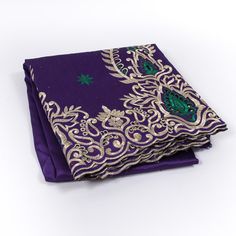 purple and gold brocaded pocket square with green accents on the edges, sitting on a white surface