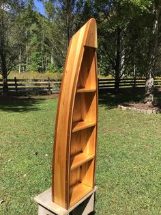 a wooden book shelf sitting on top of a grass covered field