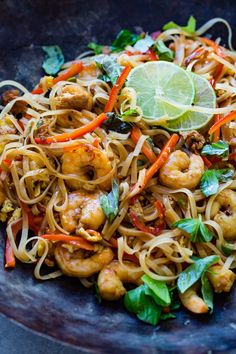 a close up of a plate of food with noodles and shrimp, carrots and cilantro