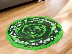 a green rug with white flowers in the center on a wooden floor next to a couch