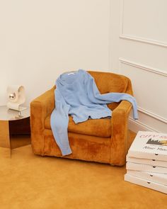 a chair with a blue blanket on top of it next to books and a table