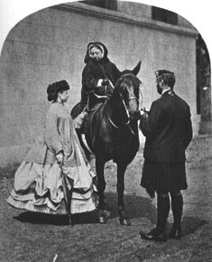 an old black and white photo of a woman on a horse with two men standing next to her