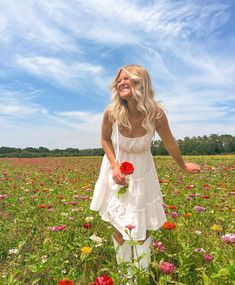 a woman standing in a field with flowers