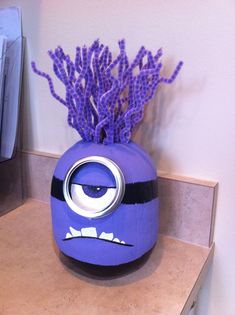 a purple vase with an angry face painted on it and some purple flowers in the middle