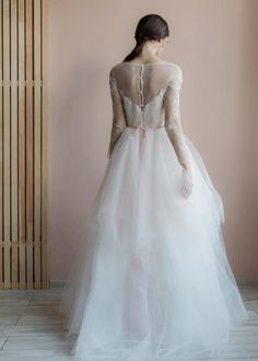 the back of a woman in a wedding dress with long sleeves and sheer tulle