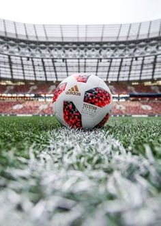 a soccer ball sitting on top of a field next to an empty bleachers