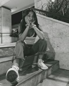 a woman sitting on the steps with her hand under her chin and looking at the camera