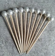 a bunch of wooden sticks with white pearls on them sitting next to each other in front of a gray background