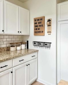 a kitchen with white cabinets and marble counter tops, along with a sign that says the lord has done great things for us