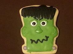 a cookie shaped like a green monster with black hair