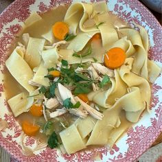 a pink and white plate topped with pasta and veggies