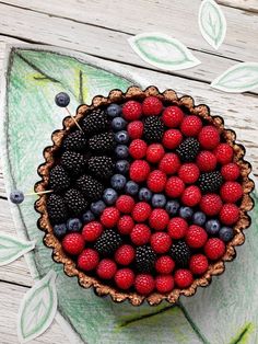 a pie with berries, raspberries and blueberries in it on top of a wooden table