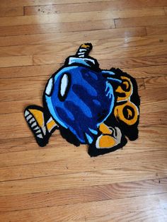 a blue and yellow fish rug sitting on top of a hard wood floor next to a wooden floor