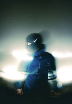 a person wearing a blue jacket and mask in the dark with lights behind them,