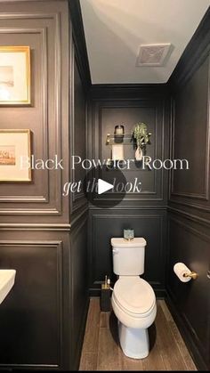 a bathroom with dark wood paneling and white toilet in the center, along with pictures on the wall