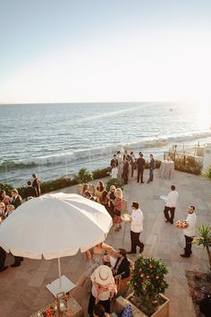 a group of people standing on top of a patio next to the ocean