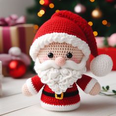 a crocheted santa clause doll sitting on a table next to a christmas tree