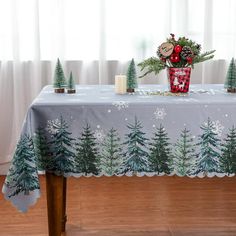 a table covered with a christmas themed table cloth and candles on top of it, in front of a window