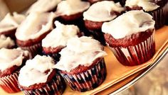 red velvet cupcakes topped with white frosting on a platter, ready to be eaten