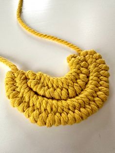 a yellow rope necklace is shown on a white surface