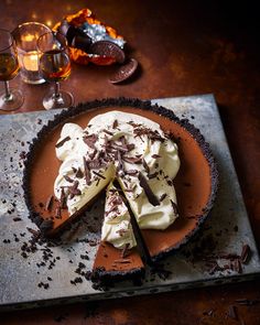 a chocolate pie with whipped cream and chocolate shavings on the top, surrounded by wine glasses