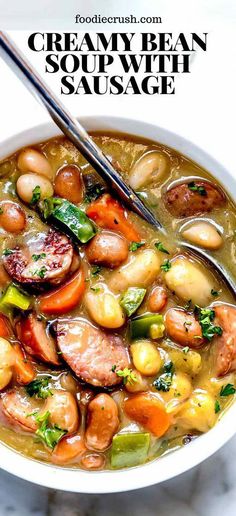 a bowl of creamy bean soup with sausage and beans is shown on a marble surface