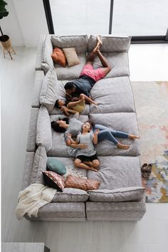 four people laying on a couch with their arms in the air while one person lays down