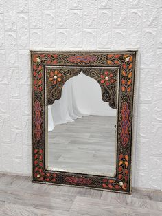 an ornate mirror on the floor in front of a white wall