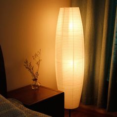 a lamp that is on top of a table next to a vase with flowers in it