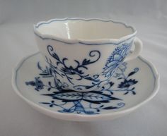 a blue and white tea cup on a saucer with matching saucer, sitting on a white tablecloth