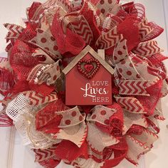 a red and beige mesh wreath with a love lives here sign