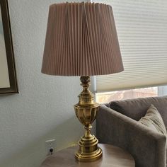 a gold lamp sitting on top of a wooden table next to a gray couch in a living room