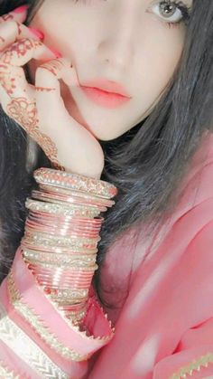 a woman with long black hair wearing pink and gold jewelry