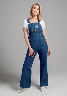 At the rounded bib of these denim overalls from Aussie brand Princess Highway, a beautifully embroidered blue hummingbird has swooped in to draw nectar from vibrant floral blooms. Made from a cotton denim fabric in a medium blue wash, these fitted overalls boast classic hardware at the adjustable shoulder straps with buckles at the bib and side-waist button closure. Featuring criss-cross straps, pockets at the front and back, and a retro-chic flare leg silhouette, these cheerful overalls are sup Fitted Overalls, Jean Upcycle, Embroidered Overalls, Plus Size Vintage Clothing, 60s Mod Fashion, Blue Hummingbird, Designer Plus Size Clothing, Outfits 70s, Princess Highway