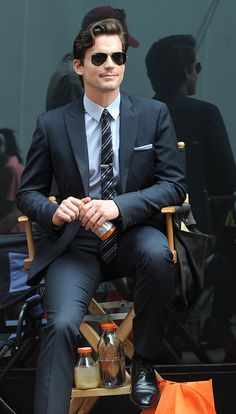 a man in a suit and sunglasses sitting on a chair