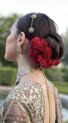 a woman with red flowers in her hair wearing gold jewelry and an elaborate head piece