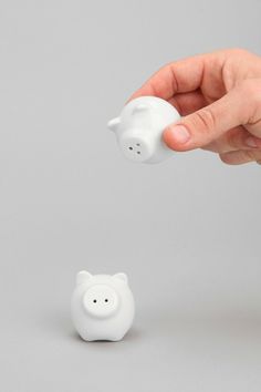 a hand is throwing a coin into a small piggy bank on a gray background