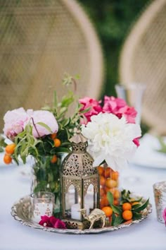 a tray with flowers and candles on top of a white table cloth covered tablecloth