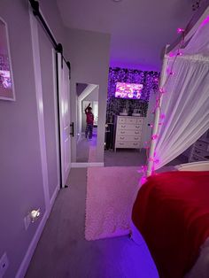 a woman is standing in the doorway of her bedroom with purple lights on and pink bedding