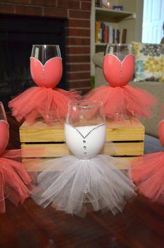 some wine glasses are sitting on top of a wooden box with tulle skirts around them