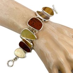 "What a stunning selection of stones this bracelet has! This is a vintage sterling silver bracelet that is created with glowing brown tiger eye, mother-of-pearl and deep red and black jasper stones! This is a designer piece by Whitney Kelly. The earthy shades make up a beautiful color selection. They are set into a sterling bezels. The pieces are nice and big. The silver is shiny. The bracelet conforms easily to your wrist so it is comfortable to wear. The clasp is a toggle. Beautiful piece to w Brown Natural Stones Jewelry For Collectors, Collectible Brown Jewelry With Natural Stones, Brown Gemstone Bracelet, Black Jasper, Brown Tiger, Brown Tiger Eye, Pearl Vintage, Vintage Bracelet, Bracelet Sterling Silver