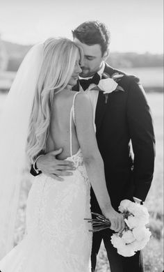 a bride and groom kissing in the field