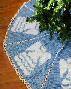 a blue crocheted tablecloth with white elephants on it and a pine tree branch