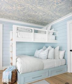 a bedroom with blue walls and white bedding on the bottom bunk is decorated with palm leaf wallpaper