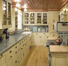 a large kitchen with wooden floors and white cupboards on the walls, along with wood flooring