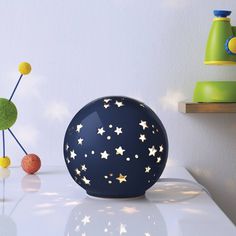 a blue vase with stars on it sitting next to other items in front of a white wall