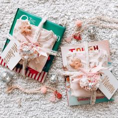 two small dolls laying next to each other on the floor with tags and ornaments around them