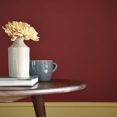 a small vase with a flower in it sitting on a table next to a book