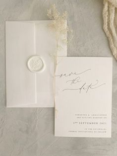 the wedding stationery is laid out on top of an envelope with a wax stamp that reads save the date